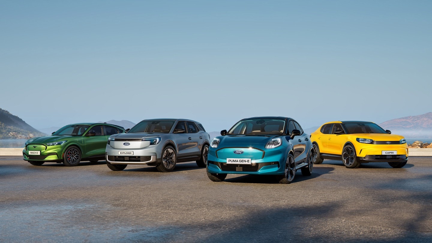 Vier Ford voertuigen opgesteld op een natte landingsbaan onder een blauwe hemel. / Quatre véhicules Ford alignés sur une piste humide sous un ciel bleu.